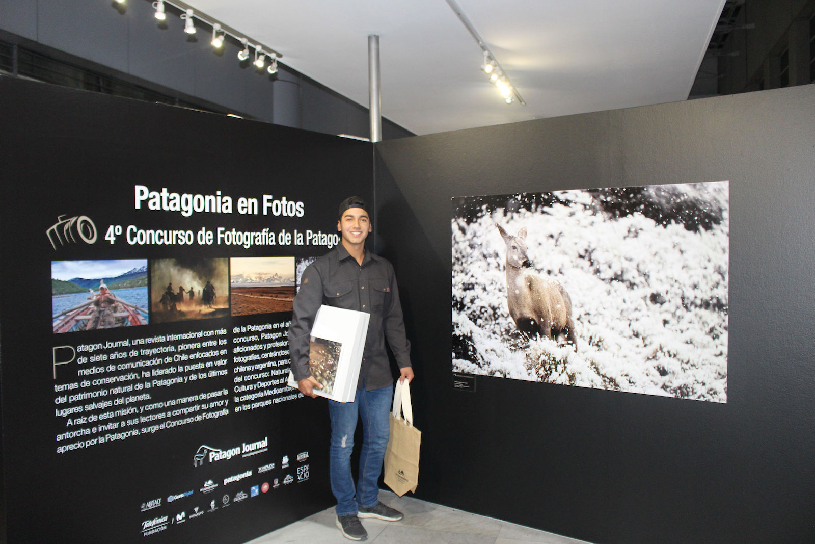 Grand prize winner, Matias Mondaca, with his prizes and in front of his winning photo of a huemul at Cerro Castillo National Park.